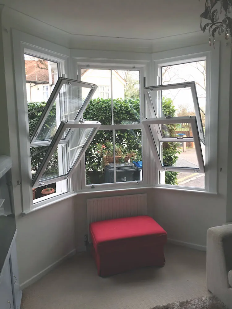 three facet white vertical sliders tilted for cleaning in bay window
