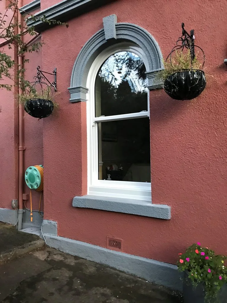 white arched vertical sliding sash window in rendered wall