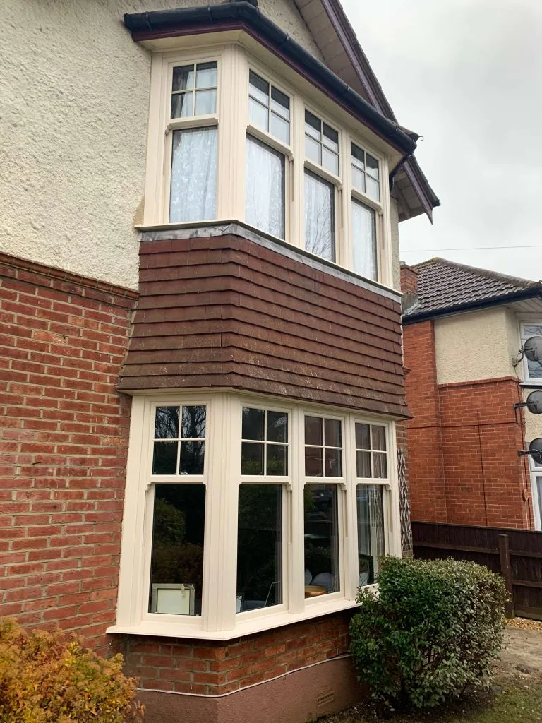 cream foil bay window in part tiled part brick wall