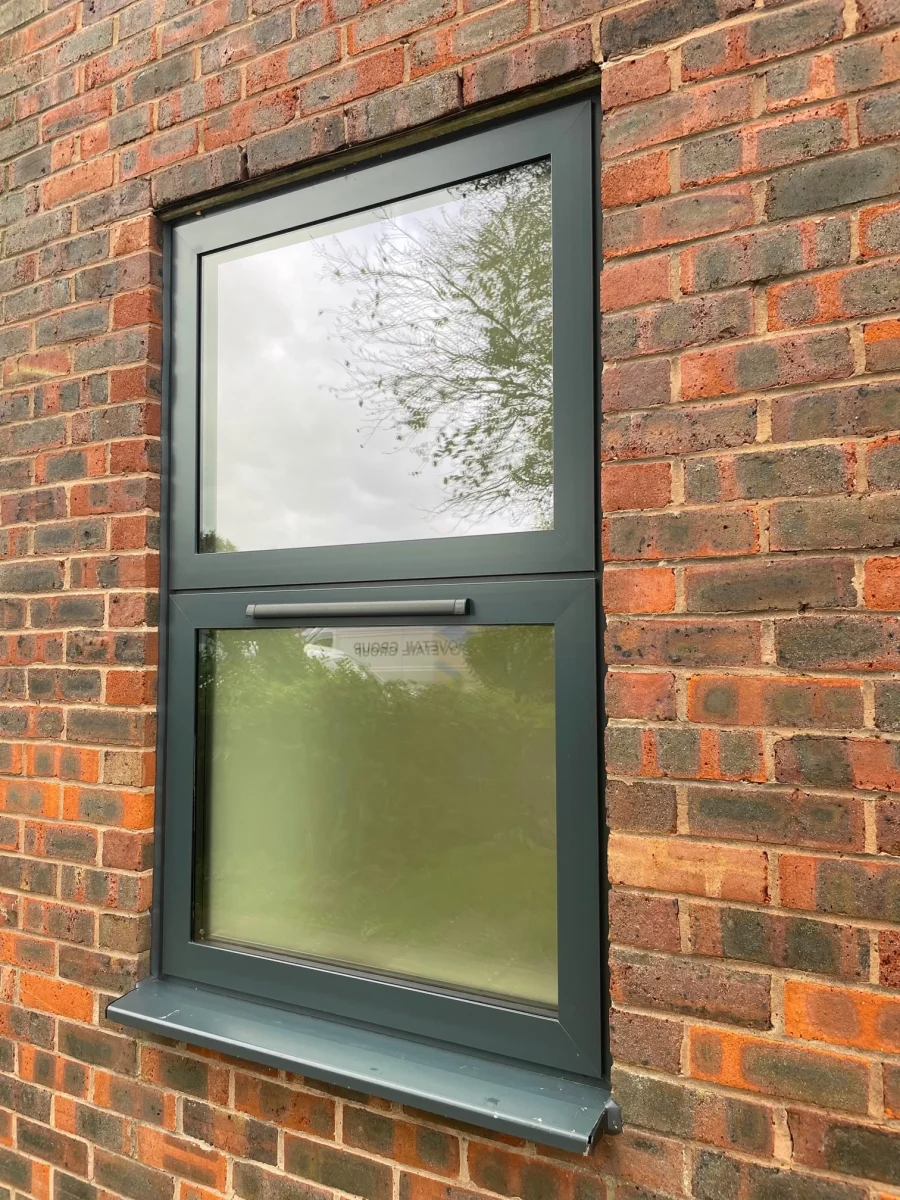 grey aluminium window in red brick wall with trickle vent